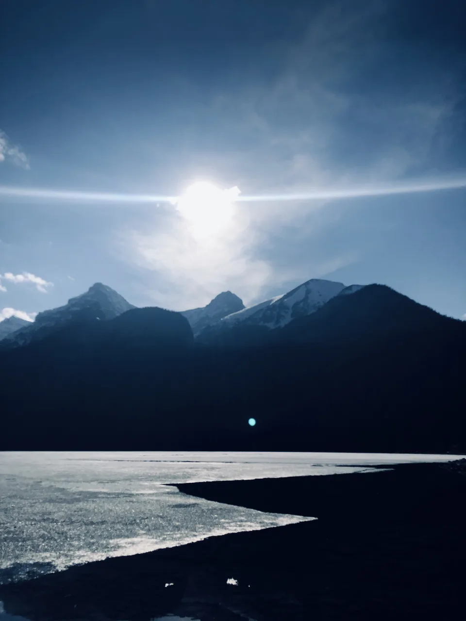 Sun flare over a frozen lake and mountains, Banff, Alberta