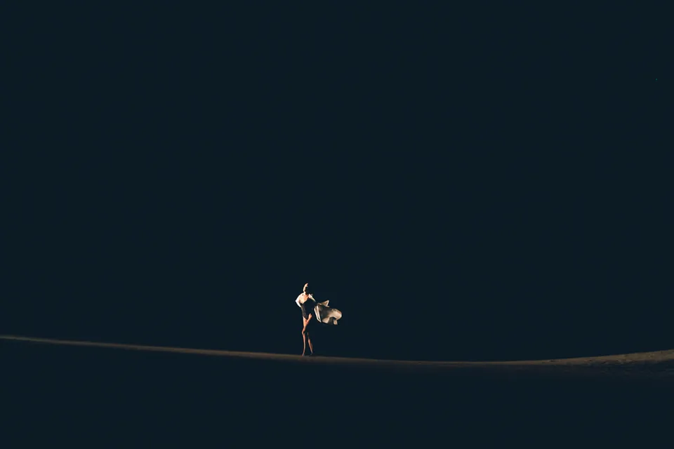 A figure lit dramatically on a dark dune at dusk, Glamis
