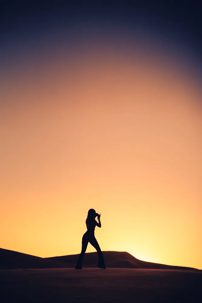 A photographer silhouetted against the sunset on the Glamis sand dunes
