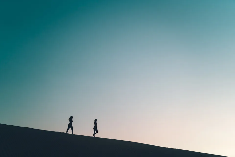 Two figures walking a dune ridge at sunset, Glamis