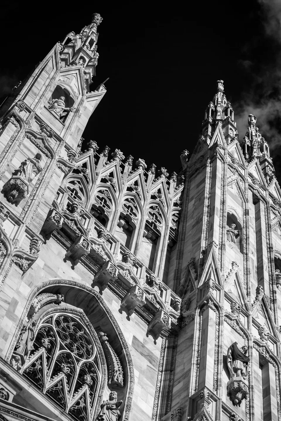 Gothic marble spires of Milan Cathedral against a dark sky, black and white