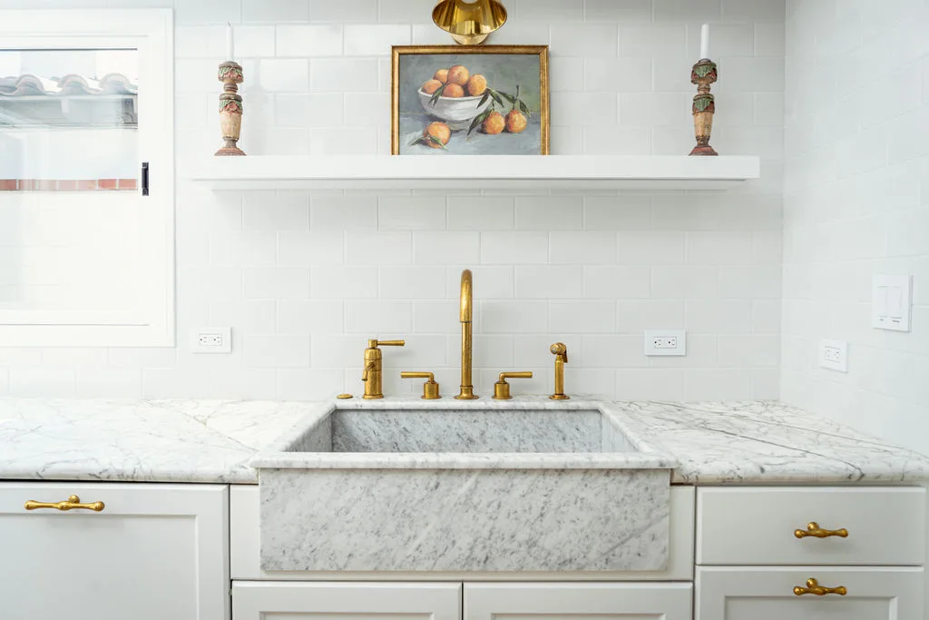 Carrara marble counters and brass fixtures beside a skylit window, 106 Via Cordova Newport Beach