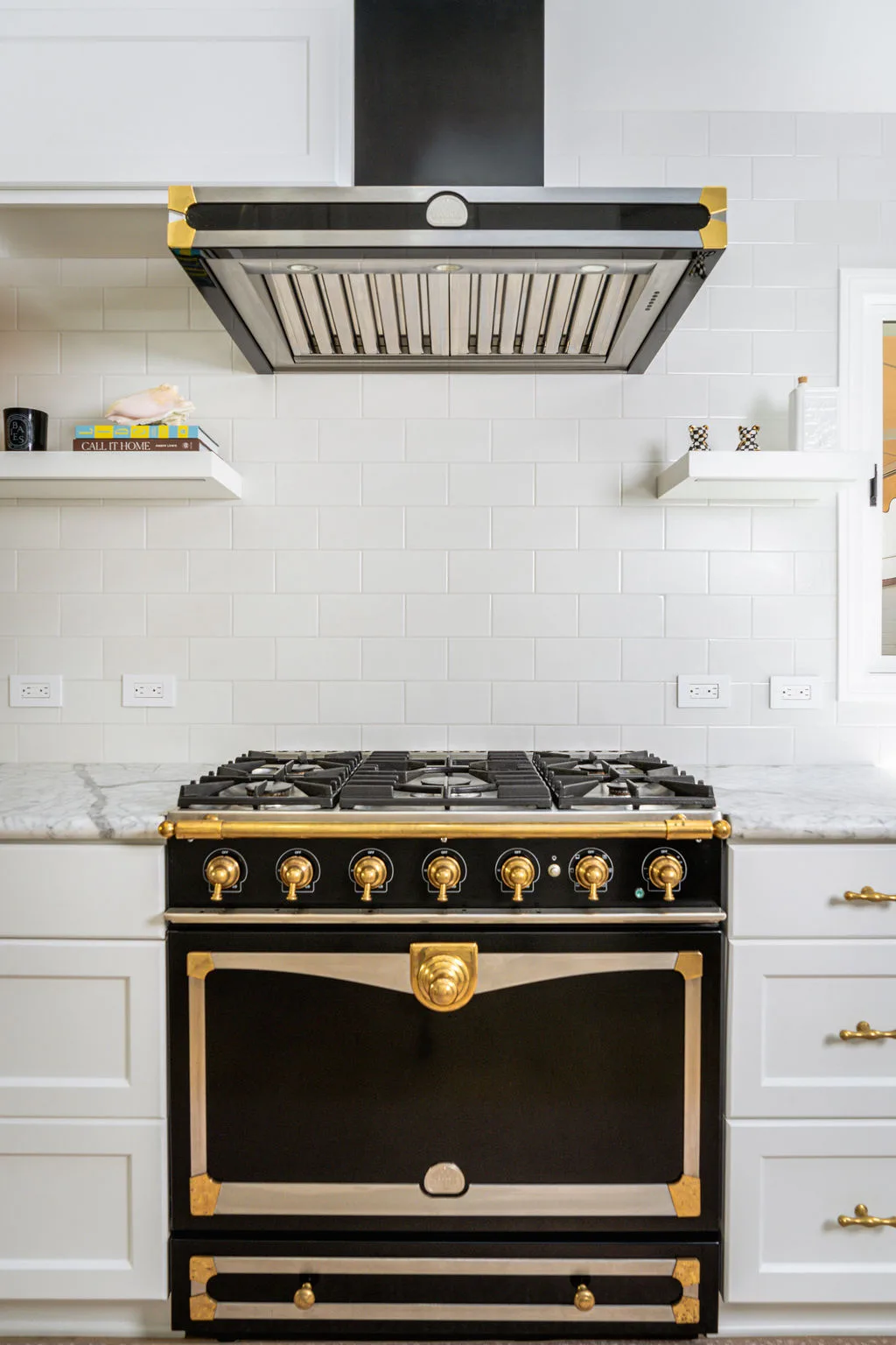 La Cornue range with polished brass knobs and stainless hood in a white Newport Beach kitchen
