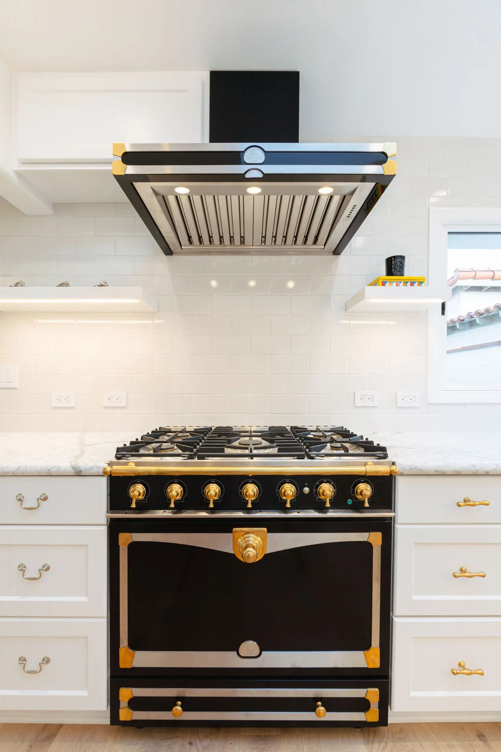 Carrara marble farmhouse sink with brass Waterworks fixtures and lit sconce