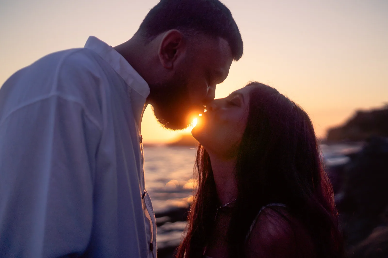 Ronak and Khushbu kissing with the sun setting directly behind them, Laguna Beach