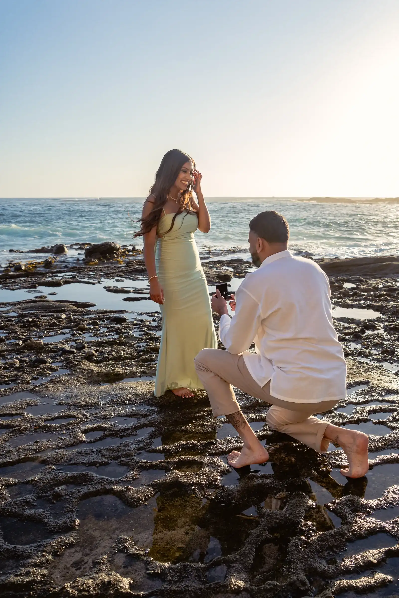 Ronak proposing on one knee on the tide pools at Treasure Island Beach in Laguna Beach