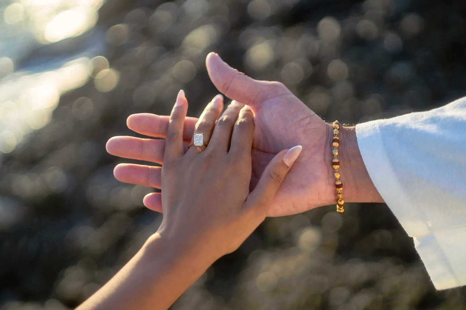 Engagement ring detail, both hands backlit by the sun at Treasure Island Beach