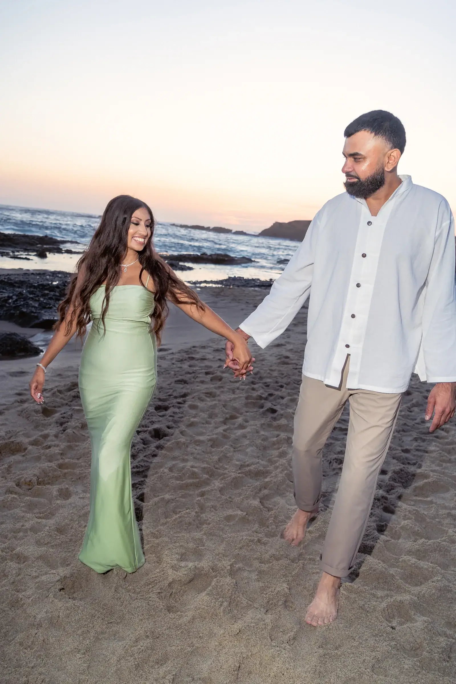 Ronak and Khushbu walking hand in hand on the sand after their proposal